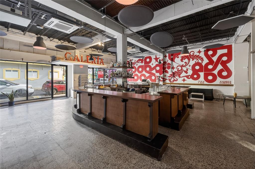 A commercial bar space features a wooden counter, concrete floors, and a large mural wall — 722 CALLE CERRA, SAN JUAN, PR