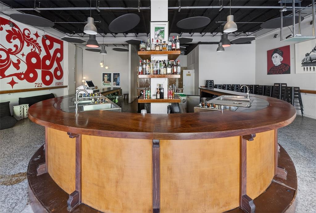 A curved wooden bar sits in the center of a room with high ceilings and artwork — 722 CALLE CERRA, SAN JUAN, PR