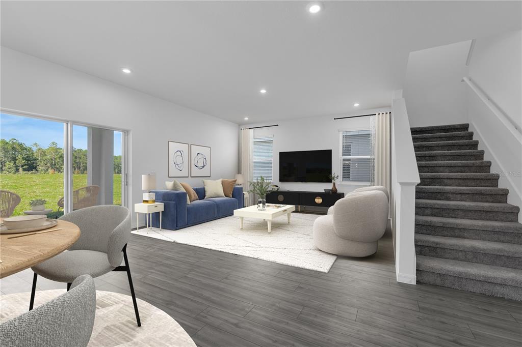 A living room features a blue sofa, white coffee table, and stairs with gray carpet — 1883 HORSETAIL DRIVE, ST CLOUD, FL