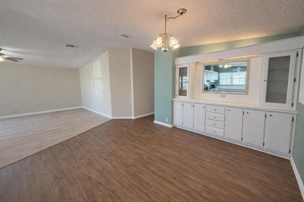 A dining area features wood-look flooring, a built-in white hutch, and a chandelier — 25308 CASA DEL LAGO LANE, LEESBURG, FL