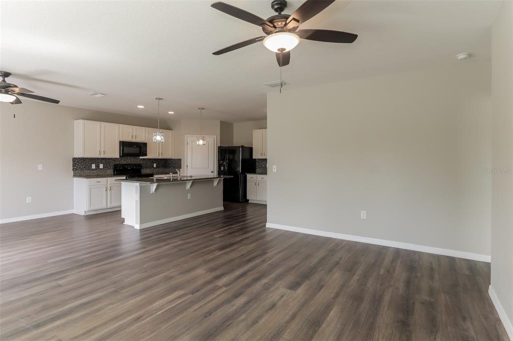An open-concept kitchen with white cabinets and a center island overlooks a spacious living area — 13628 COVEY RUN PLACE, SPRING HILL, FL