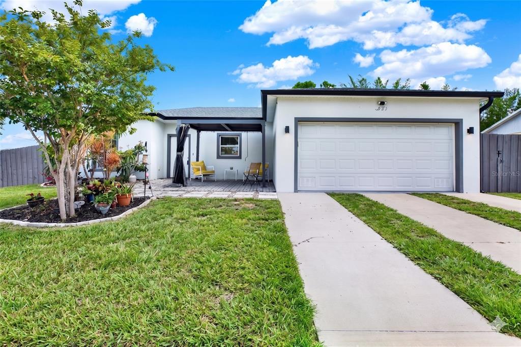 A single-story house with a white exterior, a two-car garage, and a paved front patio — 3023 MUIR STREET, HOLIDAY, FL