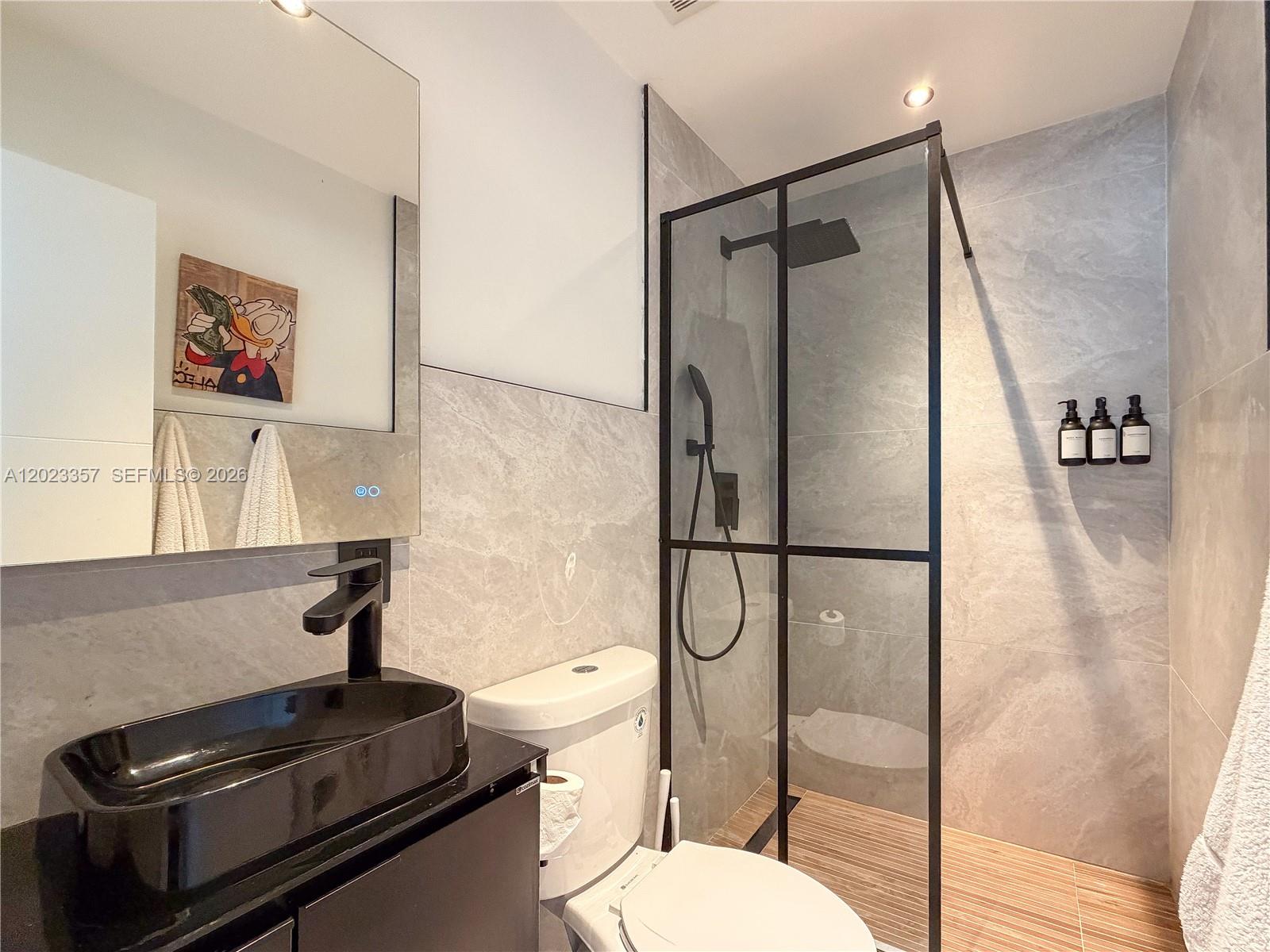 A modern bathroom features a black vessel sink, a glass-enclosed shower, and gray tile walls — 105 SW 4th Ave # 0, Hallandale Beach FL 33009, HALLANDALE BEACH, FL