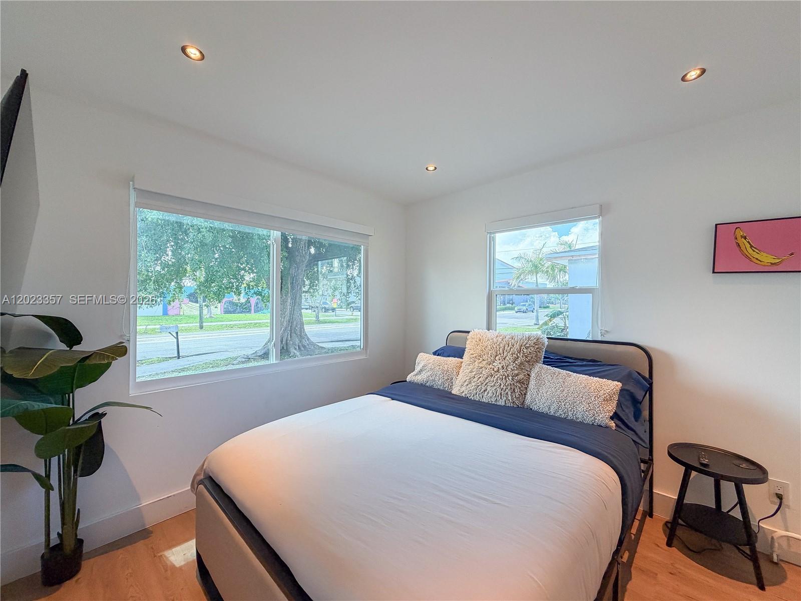 A bedroom features a bed with blue bedding, a plant, and two windows — 105 SW 4th Ave # 0, Hallandale Beach FL 33009, HALLANDALE BEACH, FL