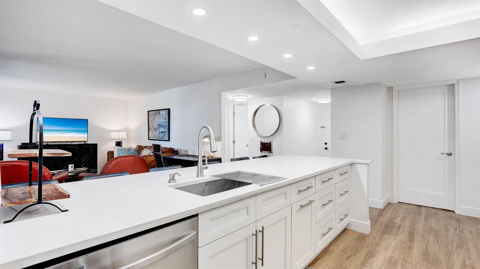 A white kitchen island with a stainless steel sink sits in a modern open-concept living space — 955 Dotterel Road # 2103, Delray Beach FL 33444, DELRAY BEACH, FL