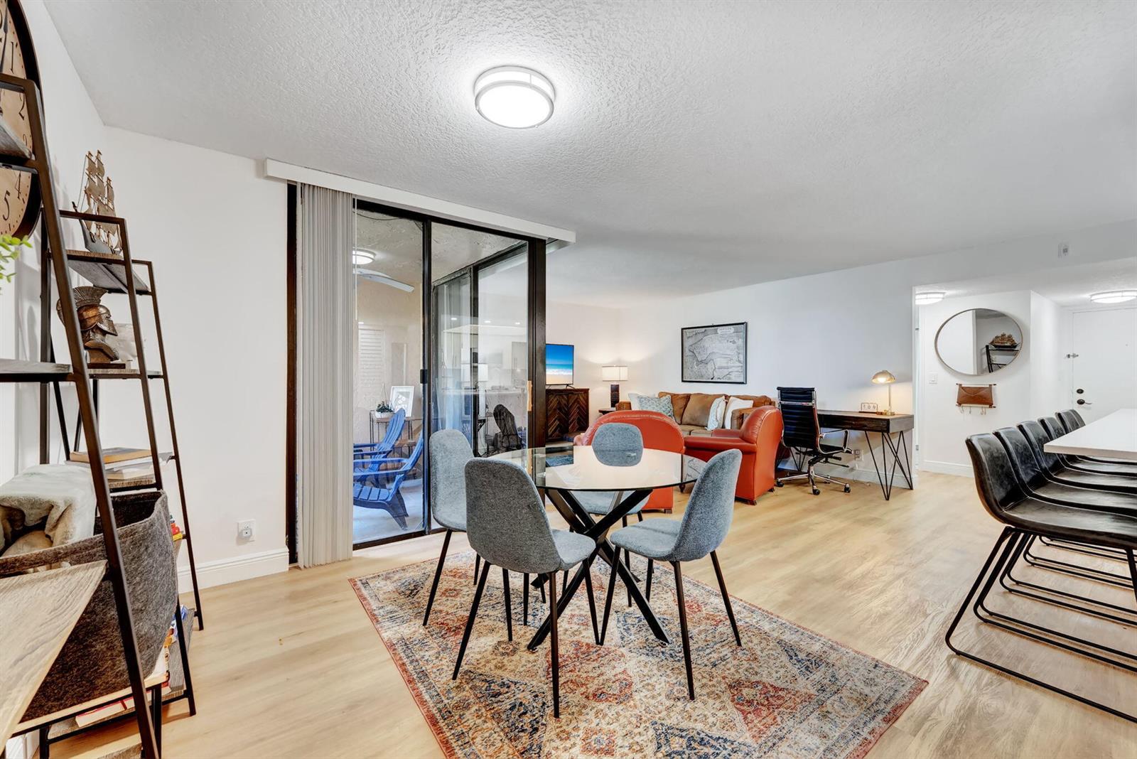 A dining area with a glass table and chairs sits adjacent to a living room — 955 Dotterel Road # 2103, Delray Beach FL 33444, DELRAY BEACH, FL