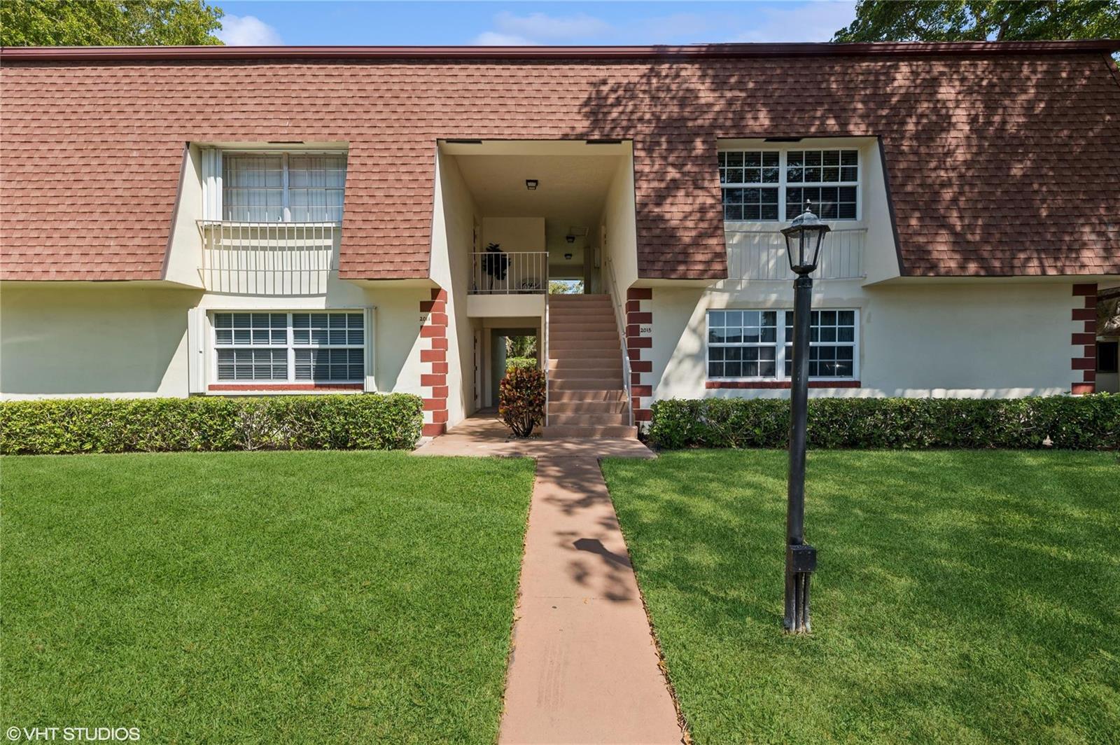 A two-story apartment building features a brown shingled mansard roof and a central staircase — 2011 NE 32nd Court # 26, Lighthouse Point FL 33064, LIGHTHOUSE POINT, FL