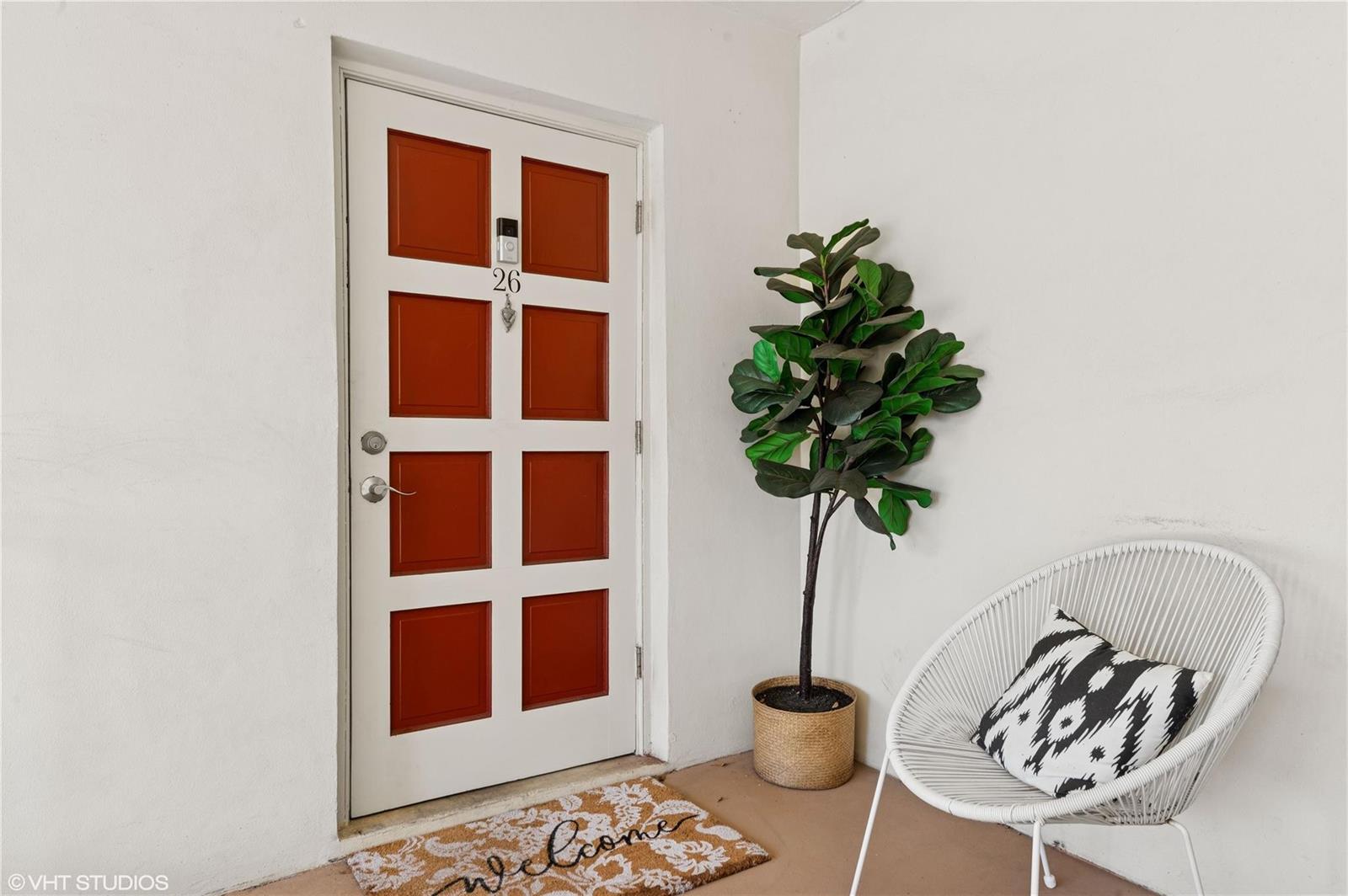 A white door with red panels, a potted plant, and a chair on a porch — 2011 NE 32nd Court # 26, Lighthouse Point FL 33064, LIGHTHOUSE POINT, FL