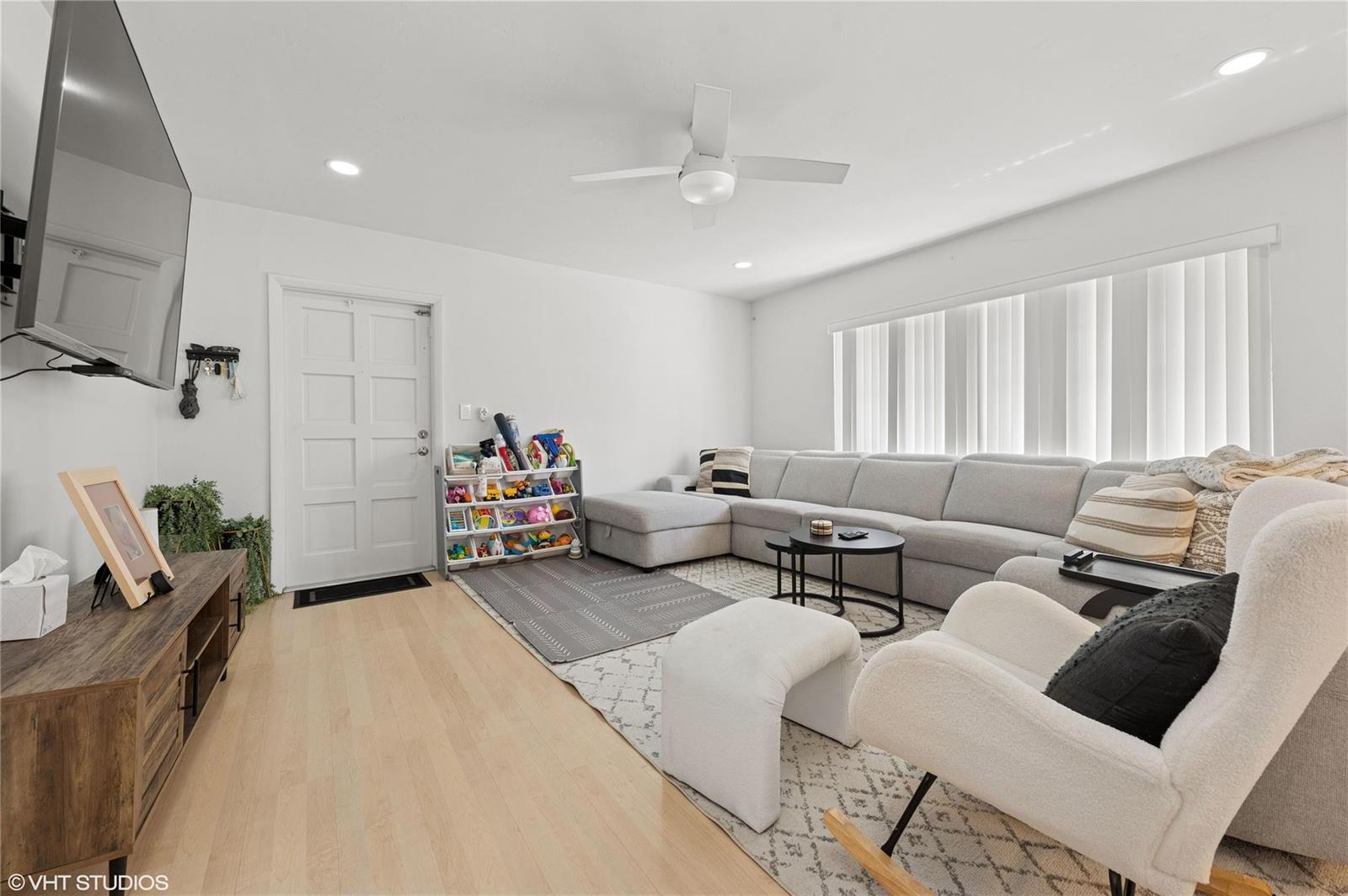 A living room features a grey sectional sofa, a white rocking chair, and light wood flooring — 2011 NE 32nd Court # 26, Lighthouse Point FL 33064, LIGHTHOUSE POINT, FL