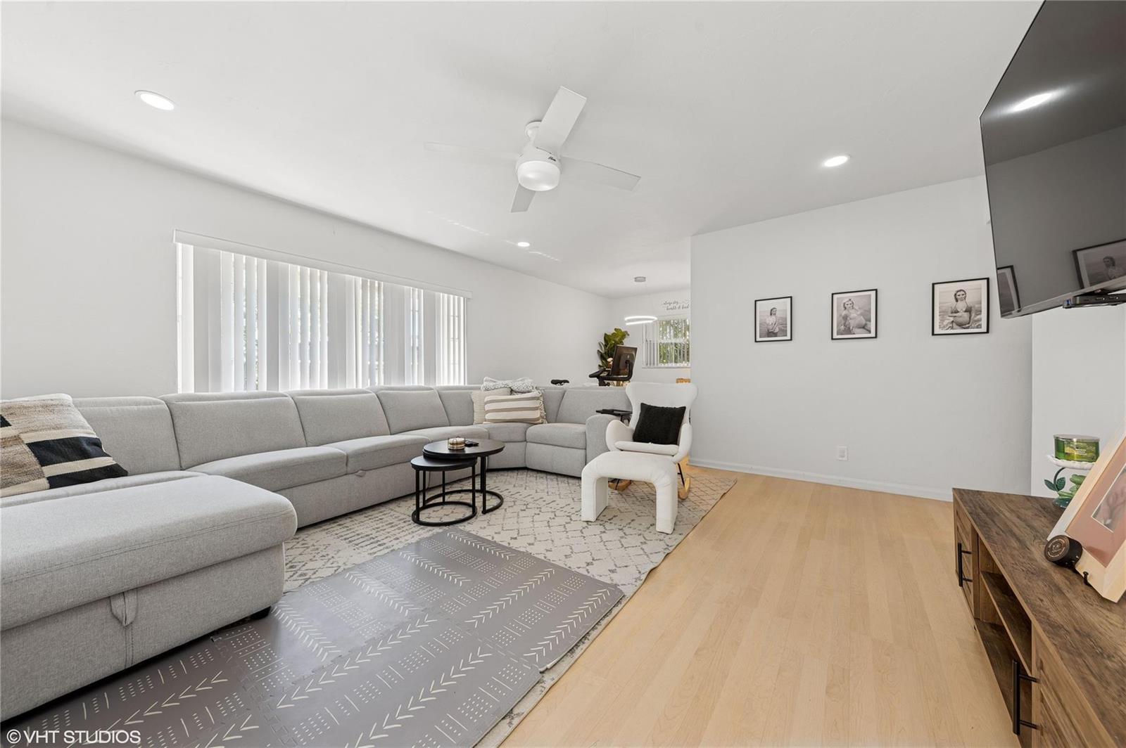 A bright living room features a large gray sectional sofa, light wood flooring, and white walls — 2011 NE 32nd Court # 26, Lighthouse Point FL 33064, LIGHTHOUSE POINT, FL