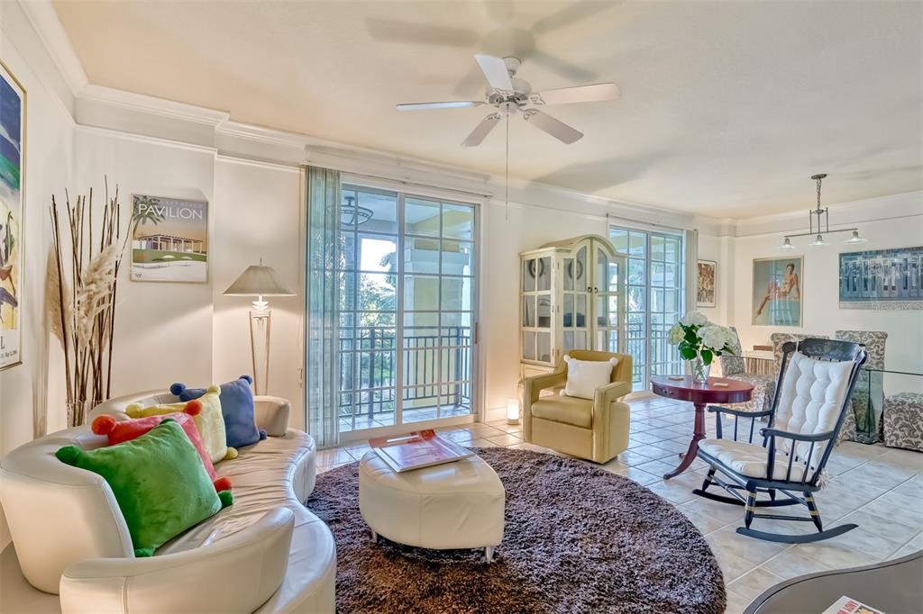 A living room with a curved white sofa, a round rug, and a rocking chair — 750 N TAMIAMI TRAIL UNIT 205, SARASOTA, FL