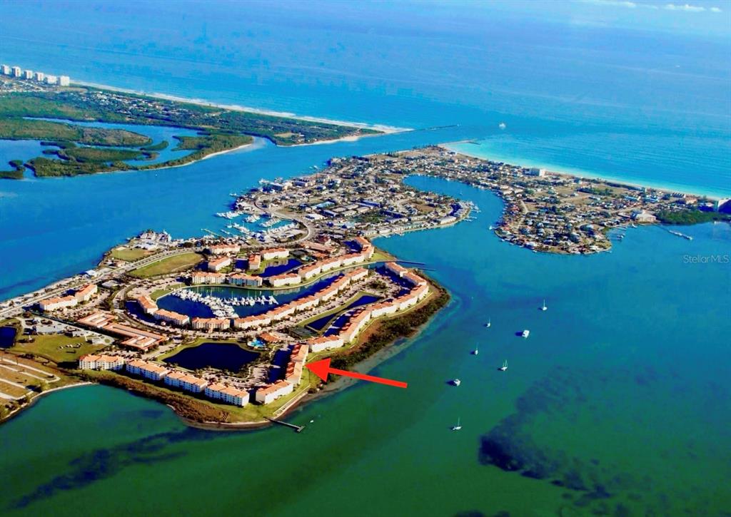 An aerial view of a waterfront residential complex with a red arrow pointing toward buildings — 29 HARBOUR ISLE UNIT PH01, HUTCHINSON ISLAND, FL