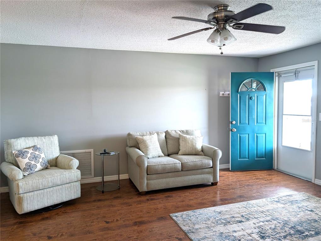 A living room features a blue front door, light gray walls, and wood-look flooring — 4415 96TH AVENUE N, PINELLAS PARK, FL