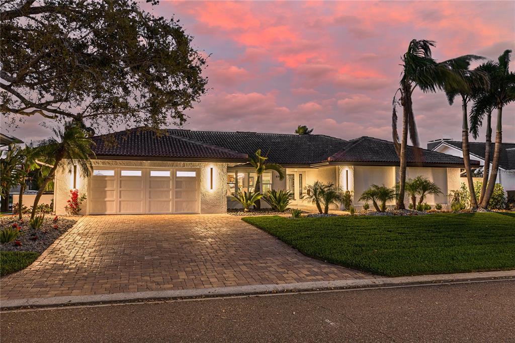 A single-story house with a paved driveway, a three-car garage, and palm trees at sunset — 4959 58TH AVENUE S, ST PETERSBURG, FL