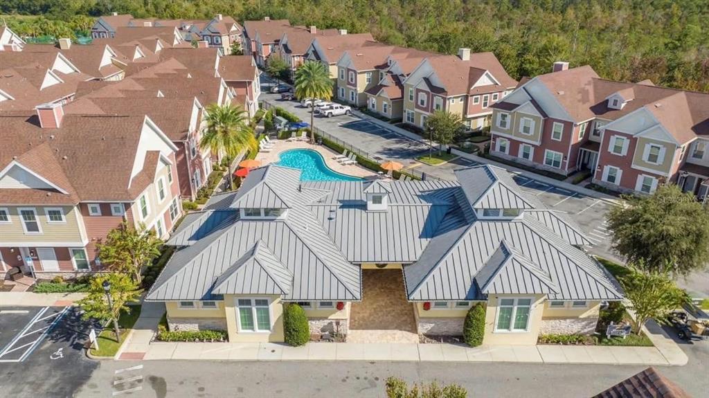 An aerial view shows a community clubhouse with a metal roof next to a swimming pool — 7571 SUNNY DREAMS LANE UNIT na, KISSIMMEE, FL