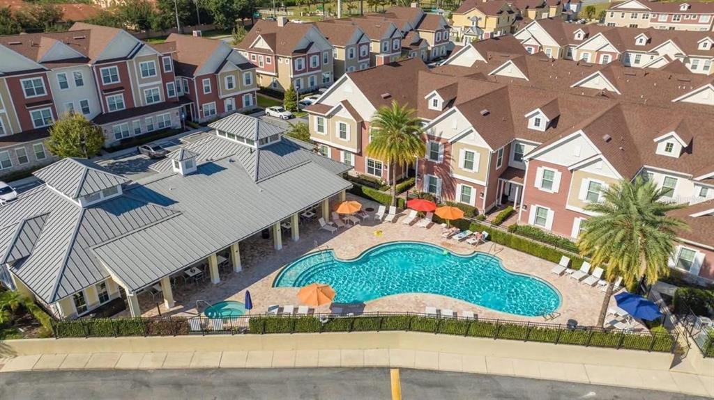 An aerial view of a community swimming pool and clubhouse surrounded by multi-story apartment buildings — 7571 SUNNY DREAMS LANE UNIT na, KISSIMMEE, FL