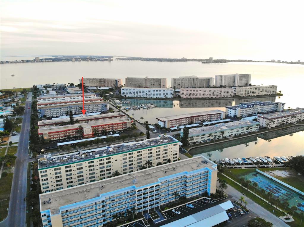 An aerial view shows multiple multi-story apartment buildings surrounding a marina and a bay — 3010 59TH STREET S UNIT 309, GULFPORT, FL