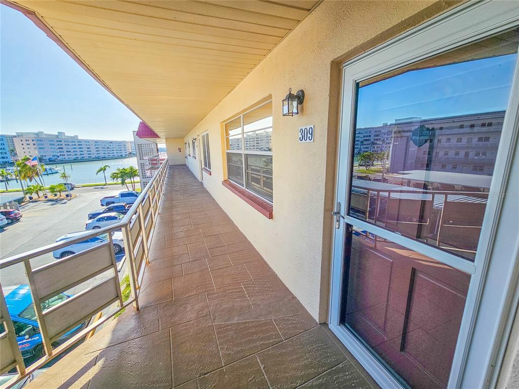 An exterior walkway with tiled flooring overlooks a parking lot and a body of water — 3010 59TH STREET S UNIT 309, GULFPORT, FL