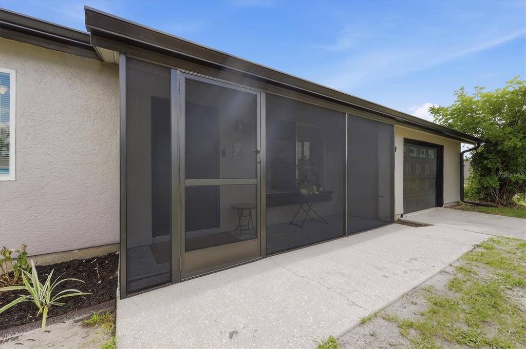 A screened-in front porch with a concrete walkway leading to a garage — 4681 NEKOOSA STREET, NORTH PORT, FL