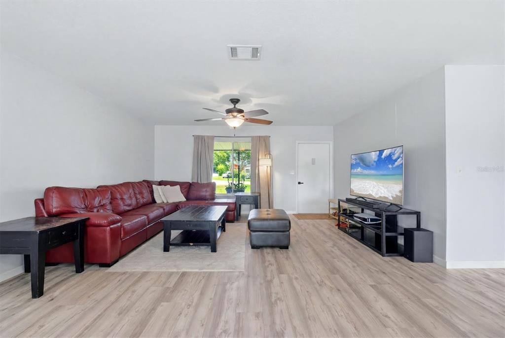 A living room features a red sectional sofa, a black coffee table, and wood-look flooring — 4681 NEKOOSA STREET, NORTH PORT, FL