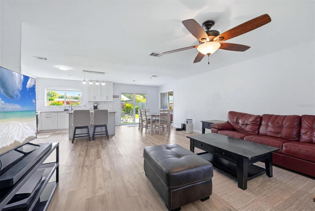 An open-concept living room and kitchen featuring light wood flooring and a red leather sofa — 4681 NEKOOSA STREET, NORTH PORT, FL
