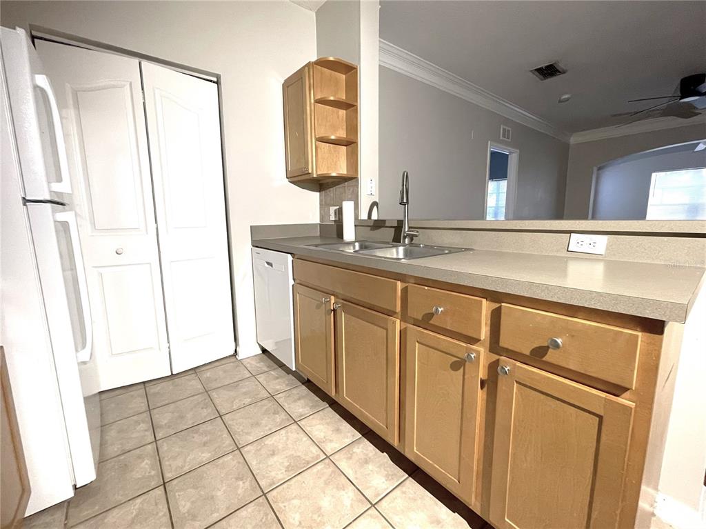 A kitchen features light wood cabinets, a stainless steel sink, and beige tile flooring — 4207 S DALE MABRY HIGHWAY UNIT 9201, TAMPA, FL
