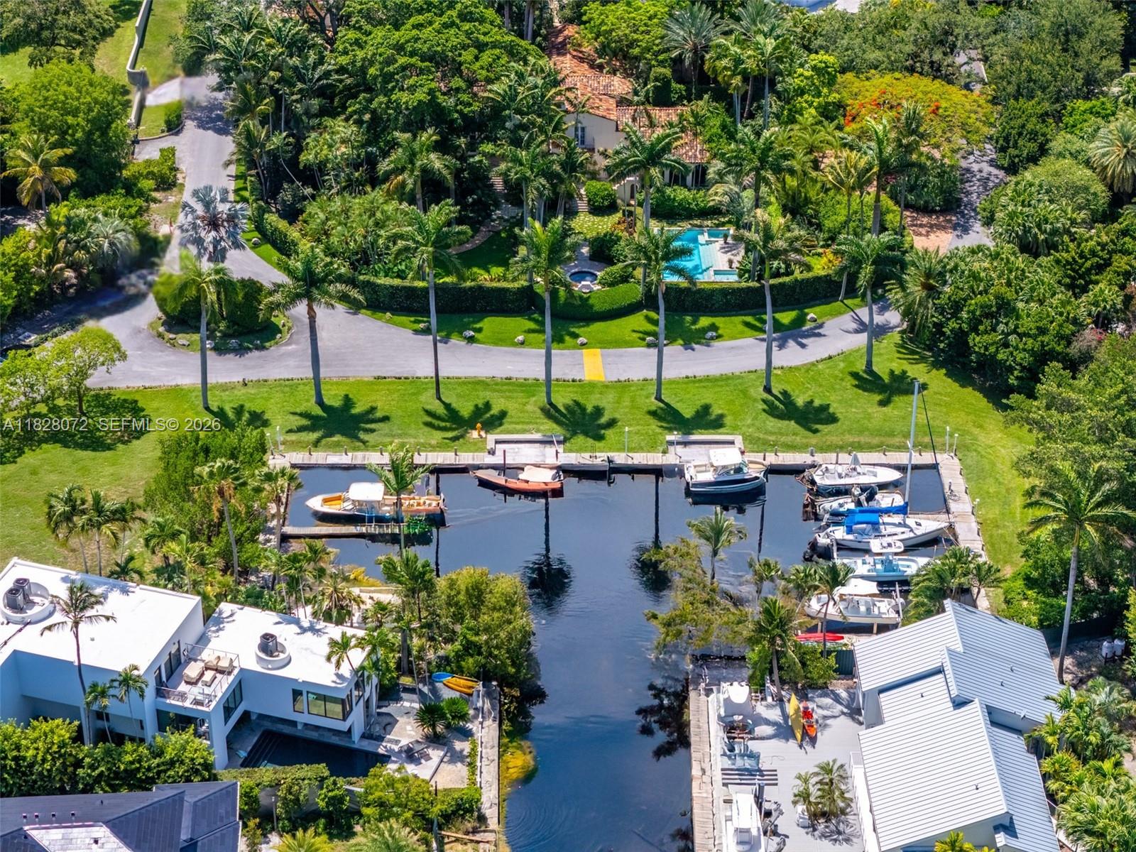 An aerial view shows a canal with docked boats between two modern waterfront homes — 3540 N Moorings Way, Miami FL 33133, MIAMI, FL