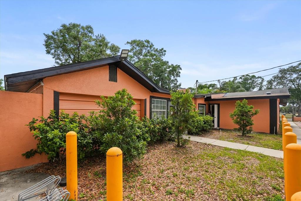 An orange house with a garage and yellow bollards in the front yard — 1436 22ND STREET, ORLANDO, FL