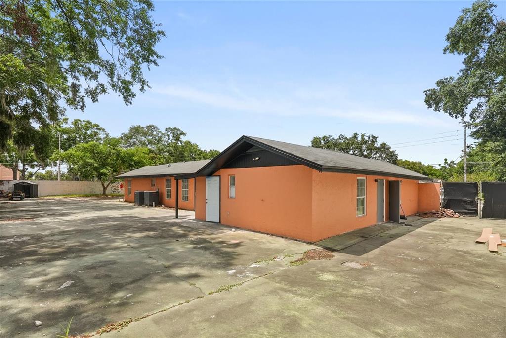 An orange, single-story building with a dark roof sits on a large, paved concrete lot — 1436 22ND STREET, ORLANDO, FL