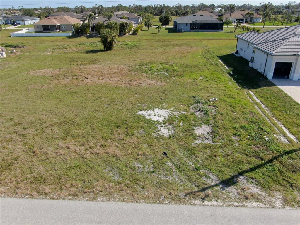An aerial view shows a vacant, grassy residential lot situated between two existing houses — 191 ROTONDA BOULEVARD S, ROTONDA WEST, FL