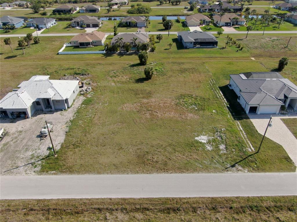 An aerial view shows a vacant residential lot situated between two newly constructed houses — 191 ROTONDA BOULEVARD S, ROTONDA WEST, FL