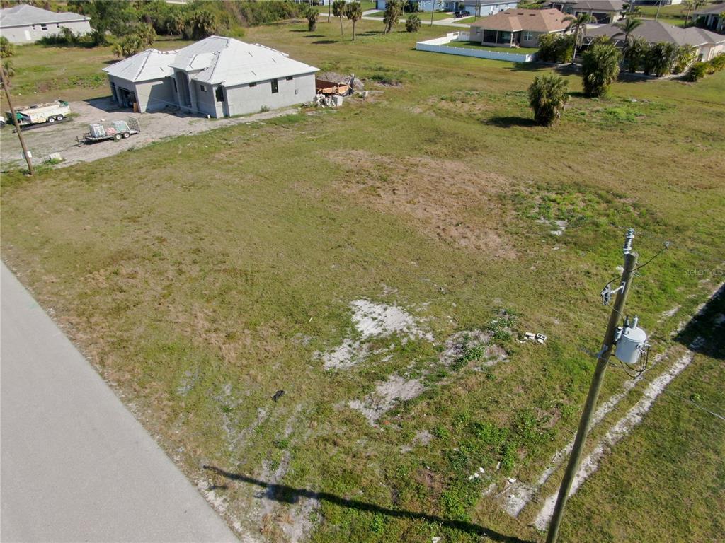 An aerial view shows a vacant, grassy residential lot next to a house under construction — 191 ROTONDA BOULEVARD S, ROTONDA WEST, FL