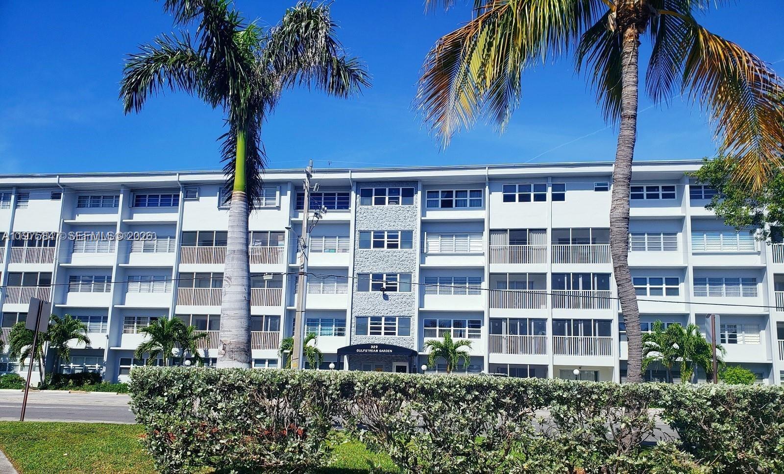 A multi-story apartment building with a gray facade, balconies, and palm trees in front — 329 SE 3rd St # 305S, Hallandale Beach FL 33009, HALLANDALE BEACH, FL
