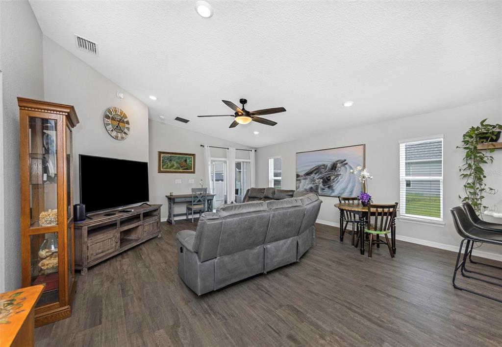 A living room features gray wood-look flooring, a sectional sofa, a television, and a ceiling fan — 3127 58TH WAY E, PALMETTO, FL