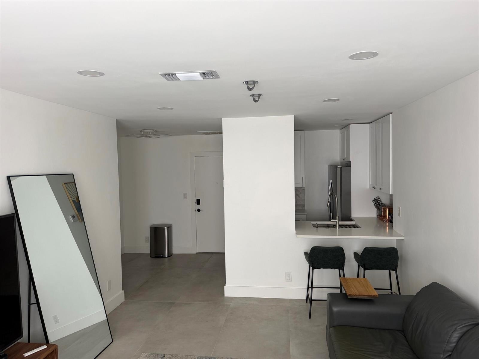 A modern apartment interior features a kitchen with white cabinets, a breakfast bar, and tile flooring — 298 SW 6th Street # 2080, Boca Raton FL 33432, BOCA RATON, FL