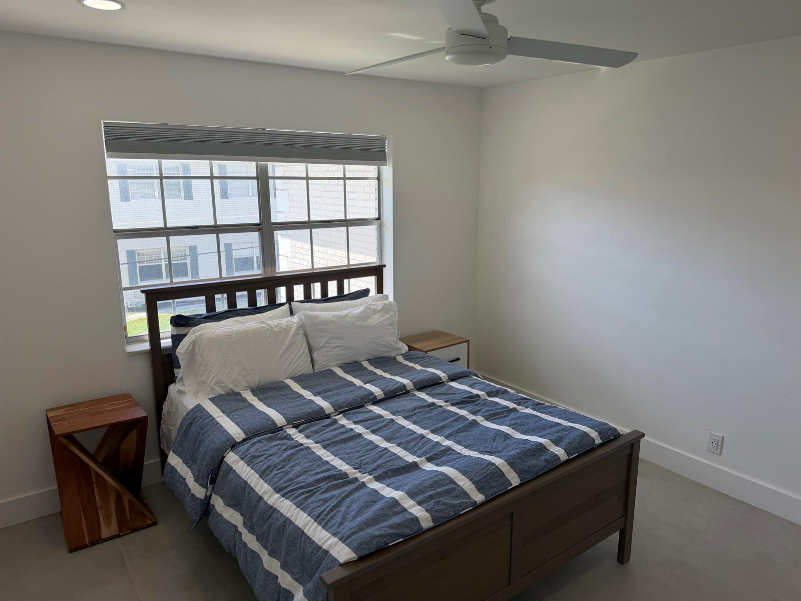 A bedroom features a wooden bed frame, blue striped bedding, and two mismatched nightstands — 298 SW 6th Street # 2080, Boca Raton FL 33432, BOCA RATON, FL