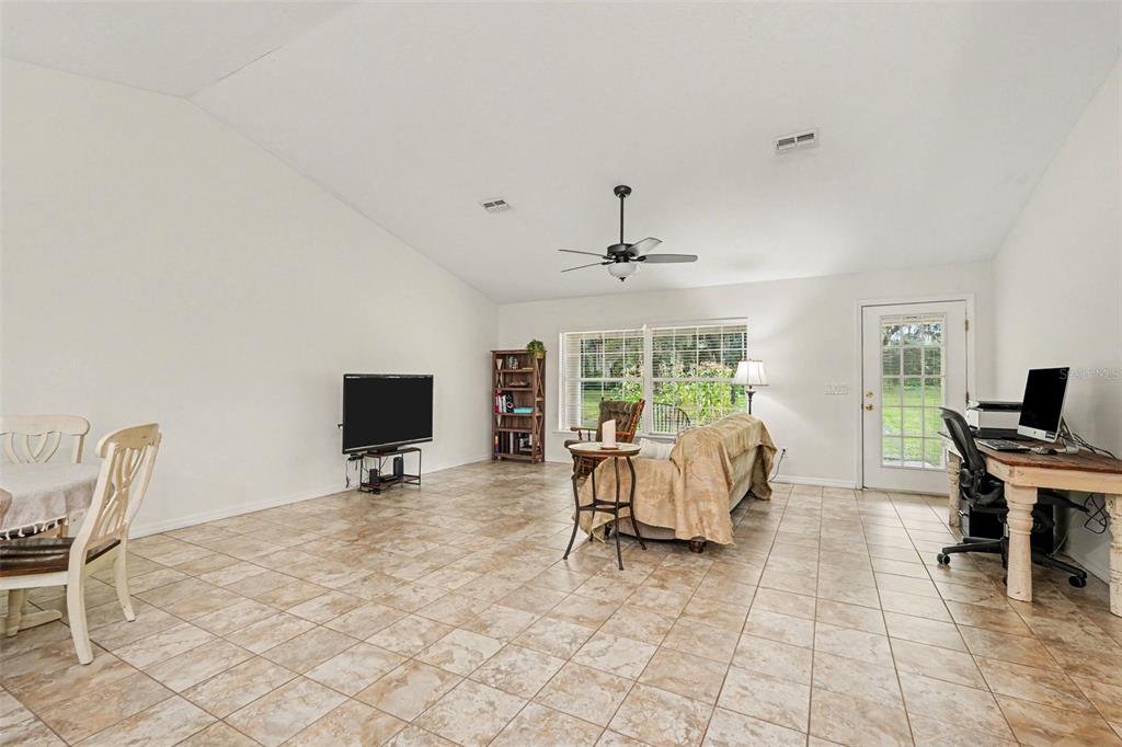 A spacious open-concept living area features a kitchen, dining space, and tiled floors — 7697 W C 476, BUSHNELL, FL