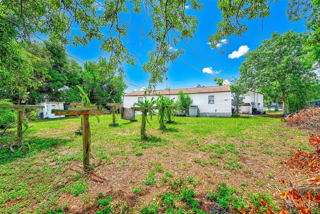 A backyard features several wooden trellises supporting dragon fruit plants in front of a house — 3257 57TH AVENUE N, ST PETERSBURG, FL