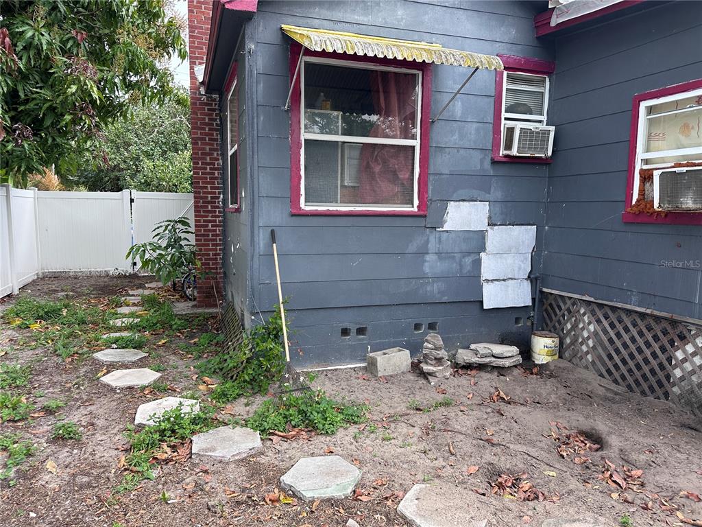 The exterior of a gray house features a brick chimney, window awnings, and a dirt yard — 2389 HIGHWAY 73, MARIANNA, FL