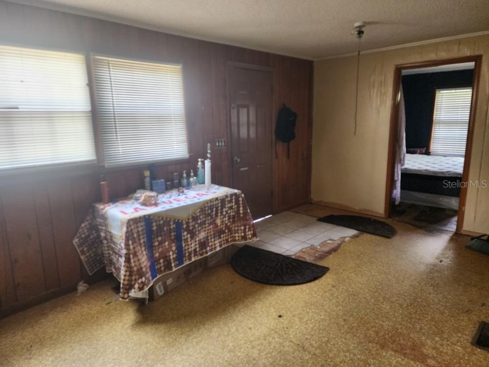 A room with wood-paneled walls, a table, a tiled entryway, and a doorway to a bedroom — 2389 HIGHWAY 73, MARIANNA, FL