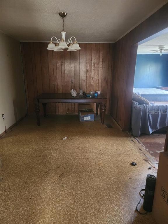 A dining area features wood-paneled walls, a chandelier, and worn flooring, opening into a bedroom — 2389 HIGHWAY 73, MARIANNA, FL