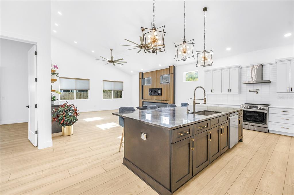 A modern kitchen features a dark island, white cabinetry, and a vaulted ceiling with chandeliers — 4907 15TH AVENUE N, ST PETERSBURG, FL