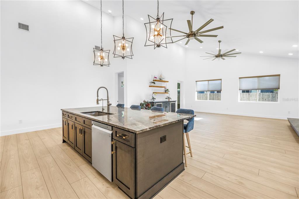 A kitchen island with a stone countertop and dark cabinets sits in a spacious room — 4907 15TH AVENUE N, ST PETERSBURG, FL
