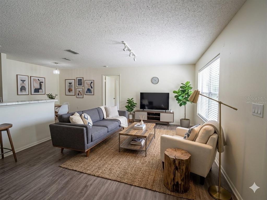 A living room features a gray sofa, a beige armchair, a wooden coffee table, and wood-look flooring — 974 LEEWARD PLACE UNIT 205, ALTAMONTE SPRINGS, FL