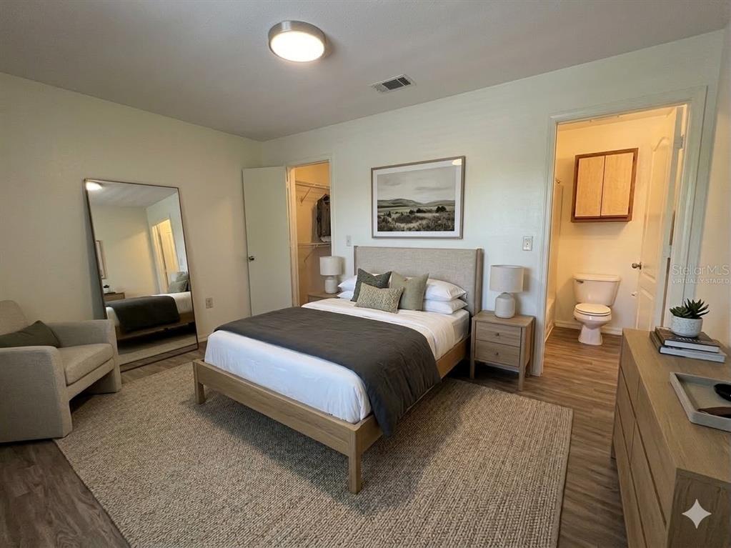 A bedroom with a bed, armchair, full-length mirror, and an attached bathroom with a toilet — 974 LEEWARD PLACE UNIT 205, ALTAMONTE SPRINGS, FL