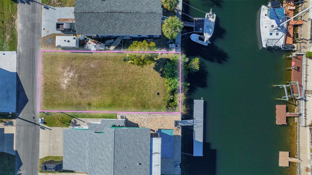 An aerial view shows a vacant rectangular waterfront lot outlined in pink next to a canal — 4029 CASA COURT, HERNANDO BEACH, FL