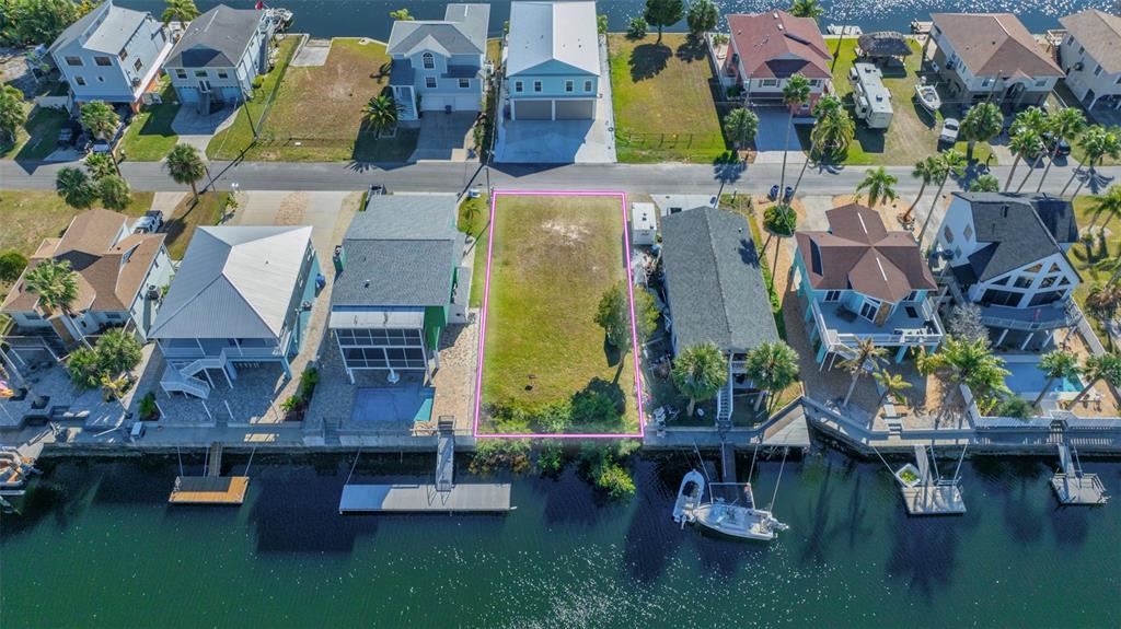 An aerial view shows a vacant waterfront lot outlined in pink between two existing houses — 4029 CASA COURT, HERNANDO BEACH, FL