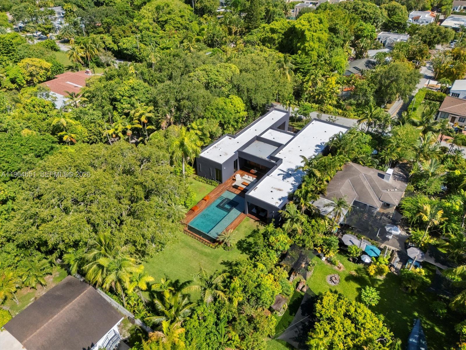 An aerial view shows a modern flat-roofed house with a swimming pool and wooden deck — 871 NE 83rd St, Miami FL 33138, MIAMI, FL