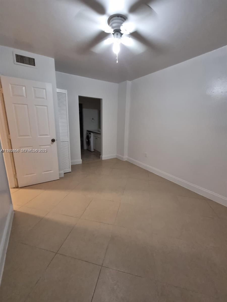 A room with light-colored tile flooring, white walls, a ceiling fan, and a doorway — 665 NE 83rd Ter # 112, Miami FL 33138, MIAMI, FL