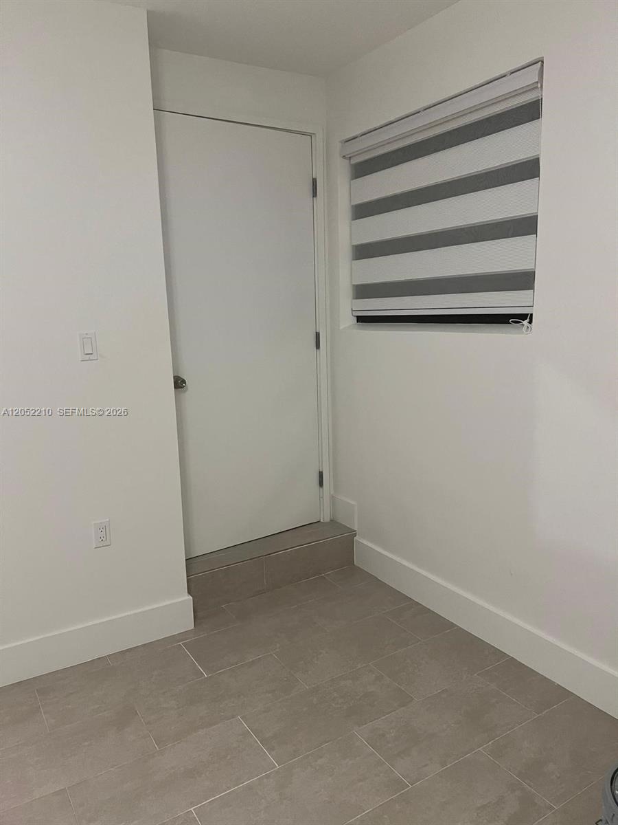 A small room features a white door, a window with striped blinds, and tiled flooring — 10822 SW 142nd Ct # 1, Miami FL 33186, MIAMI, FL
